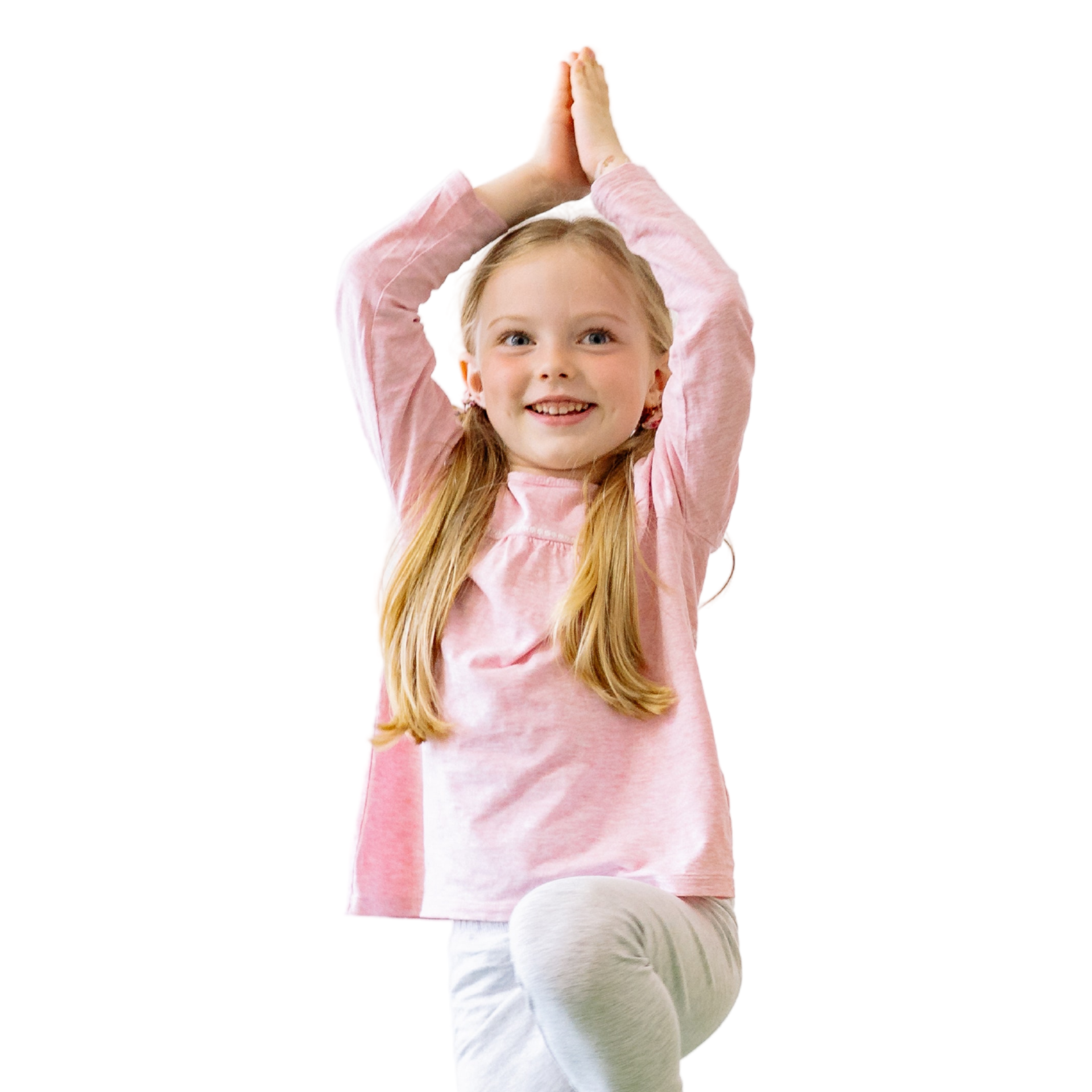 A young girl with long blond hair is doing the yoga tree pose.